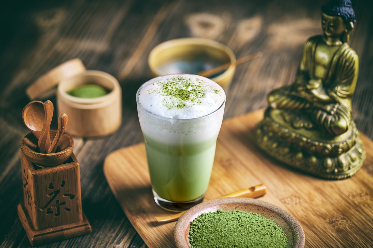 Matcha latte: la bevanda verde che conquista al primo sorso 2 vassoio con statua cinese, tazza di matcha e bicchiere di latte matcha