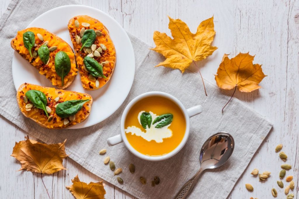 La zucca fa ingrassare? Calorie e quanta mangiarne a dieta 1 su un tavolo un piatto con bruschette con la zucca e una tazza con una vellutata di zucca