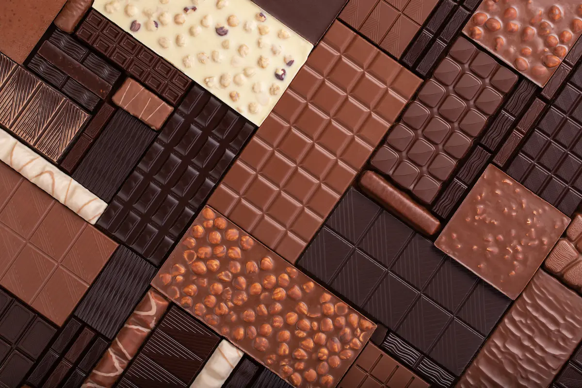 Cioccolato fondente: tipologie, calorie, benefici, quanto mangiarne a dieta 1 primo piano di tavolette di cioccolato: cioccolato fondente, cioccolato bianco e con le noci