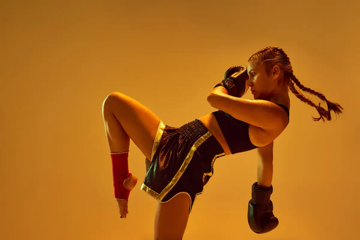Arti marziali: cosa sono, stile di combattimento, quale scegliere, elenco completo 2 su sfondo arancione ua donna con guanti da boxe e shorts si prepara a colpire un avversario immaginario mentre fa arti maziali
