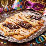 Frappe al forno: la versione leggera dei dolci di Carnevale 1 vassoio in argento con sopra le frappe al forno intorno bicchieri e mascherine e stelle filanti