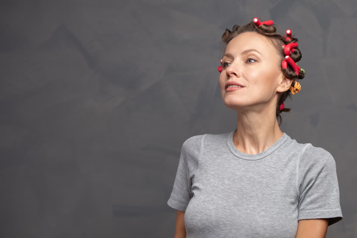 Bigodini: come usarli, quali scegliere per i tuoi capelli 2 donna con una maglietta grigia e bigodini in testa
