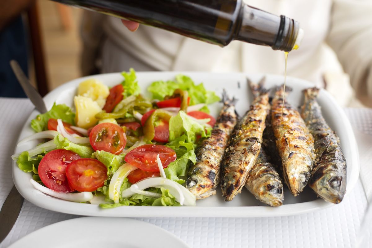 Cibi antinfiammatori: un piatto con insalata e delle sardine condite con olio di oliva