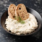 Mousse di tonno senza maionese: leggera e pronta in pochi minuti 1 ciotola nera ripiena di mousse di tonno e con due fette di pane integrale tostato