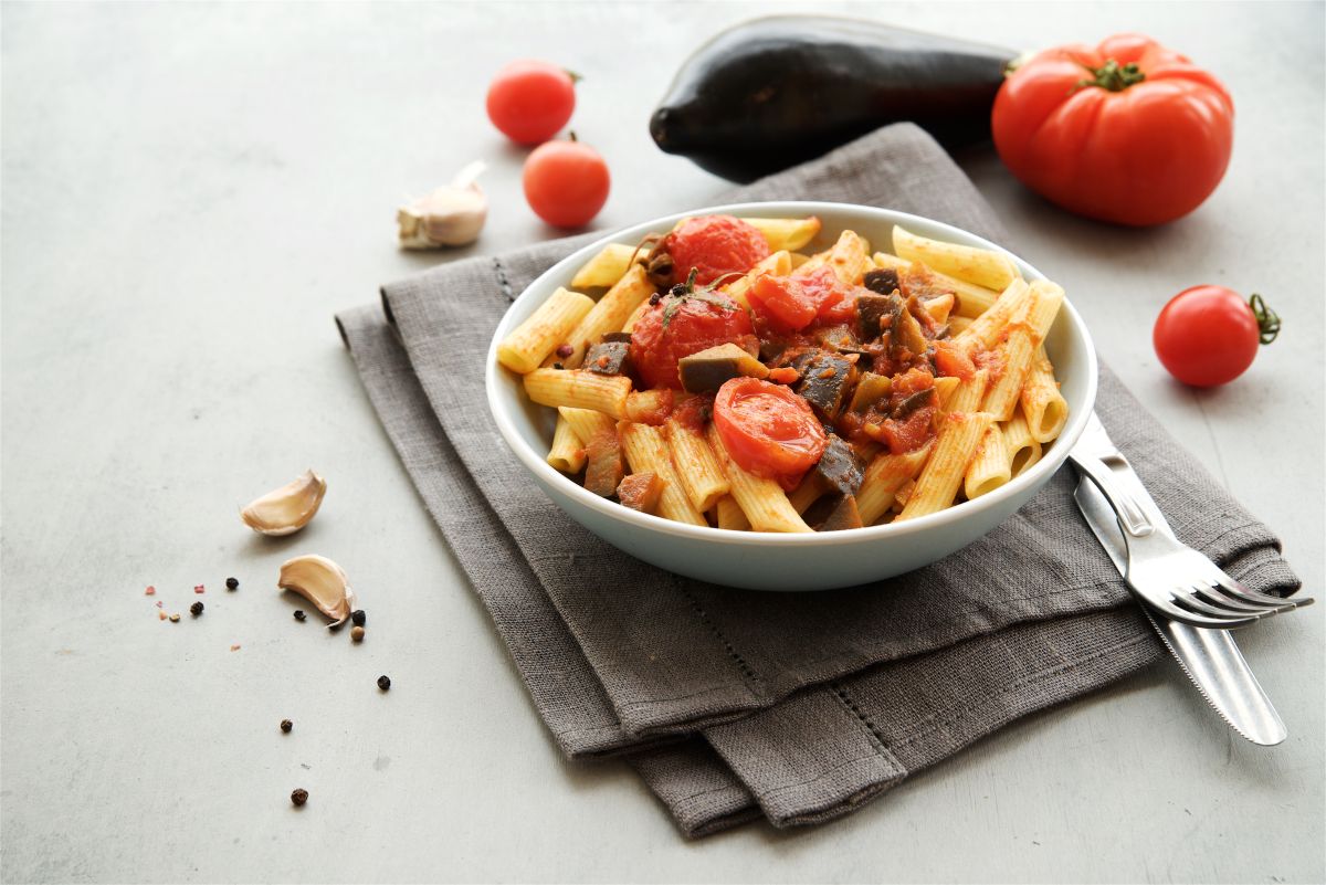 Le migliori ricette vegetariane: idee facili e gustose 7 una scodella con pasta con le melanzane, spicchi di aglio, pomodori e melanzana per preparare ricette vegetariane