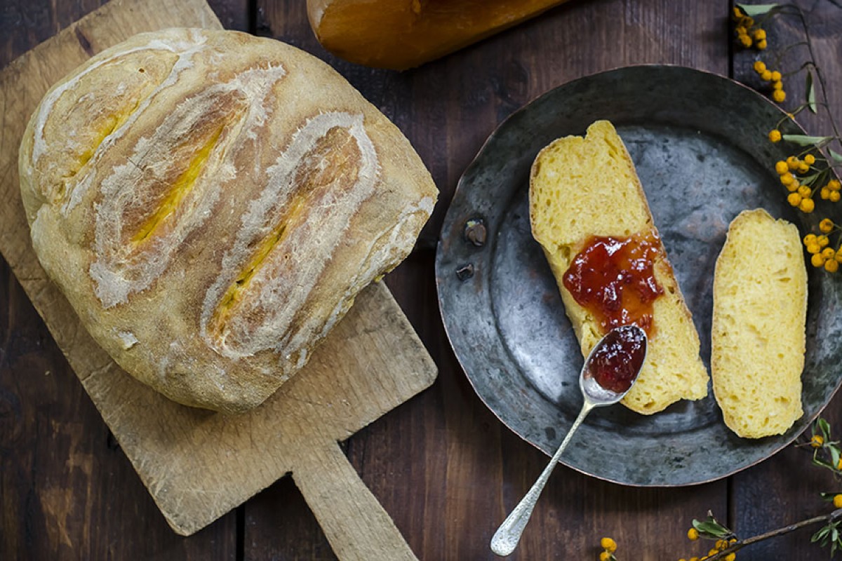 Pane fatto in casa: ricette genuine e semplici da provare 25 un tagliere di legno con una pagnotta di pane, una padella con due fette di pane e la marmellata
