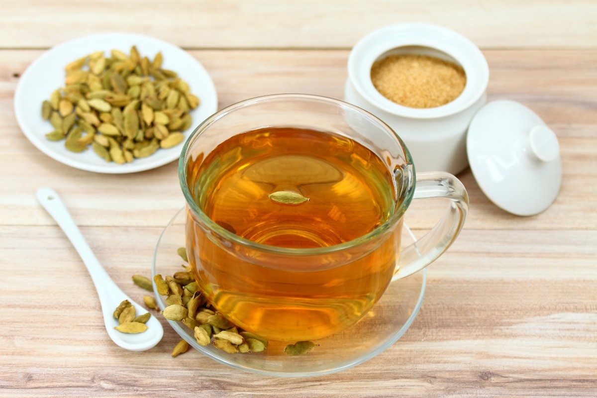 Cardamomo: a cosa serve, proprietà e usi 2 su un tavolo di legno tazza da tè con infuso di cardamomo come rimedio per sgonfiare la pancia