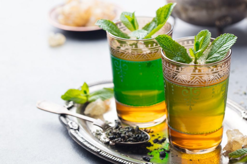 Menta: proprietà, benefici e usi in cucina e bellezza 4 su un vassoio 2 bicchieri colorati con infuso di mento e foglie di menta per sgonfiare la pancia
