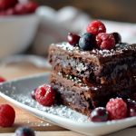 Brownies: la ricetta originale e le varianti creative e ipocaloriche 2 un piatto con una porzione di brownies e frutti di bosco