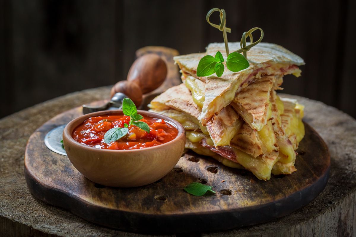 Calorie della piadina: quante sono e come influiscono sulla dieta 1 Fette di piadine farcite con accanto una ciotola con salsa di pomodoro