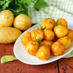 Polpette di patate: la ricetta con pochi ingredienti da provare subito! 1 piatto ovale bianco con polpette di patate accanto a tre patate e prezzemolo