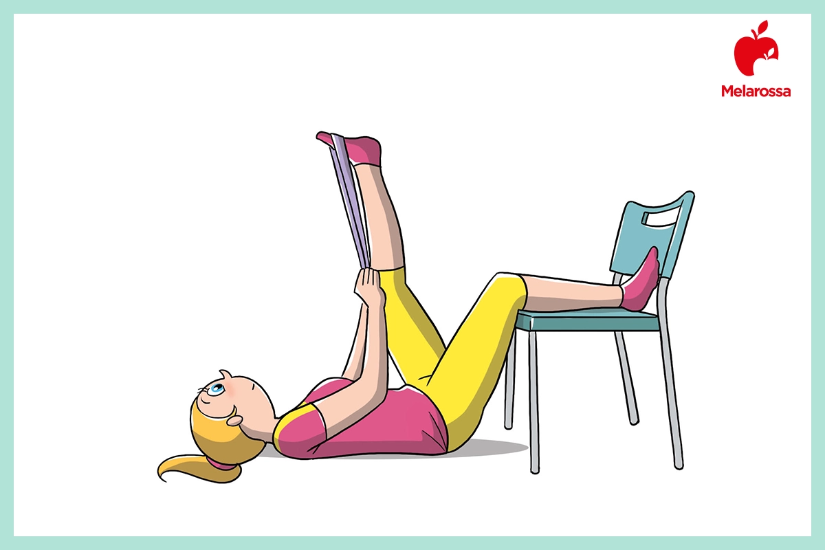 Ischiocrurali: come allenarli e allungarli per gambe forti e flessibili 8 Donna a terra che con un elastico fitness sul piede, esegue stretching degli ischiocrurali