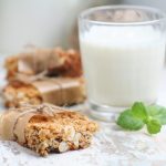 Barrette proteiche fatte in casa: uno spuntino sano per gli sportivi 1 primo piano di barrette proteiche fatte in casa con la frutta secca e dietro un bicchiere di latte