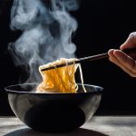 Noodles fatti in casa: la ricetta degli spaghetti giapponesi 1 ricette cinesi: su tavolo ciotola nera con noodles fatti in casa che fumano, una mano li prende con le bacchette cinesi