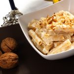 Pasta ricotta e noci: un primo piatto veloce e cremoso 1 su tavolo un piatto bianco con pasta ricotta e noci accanto 3 noci e un bicchiere di vino bianco