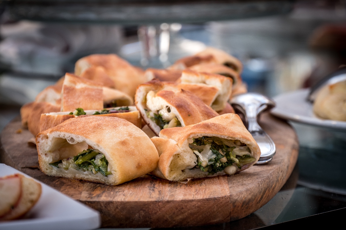 Le ricette con la scarola: dalle classiche napoletane alle varianti 1 primo piano di un tagliere di legno con una pizza di scarola al taglio pronta per essere degustata