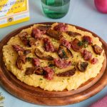 Polenta e zampone Modena IGP: un piatto unico sano e genuino 2 su tavolo azzurro, un tagliere con polenta e zampone con attorno palline di Natale e dietro una confezione di zampone Modena IGP