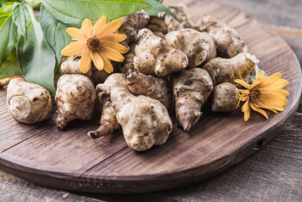 Topinambur: cos'è, proprietà e controindicazioni 3 Alcuni topinambur, tuberi, su un tagliere in legno