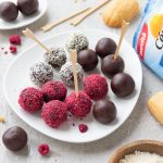 Cake pops senza zuccheri: un dolce sano e gustoso 1 piatto bianco con palline ai lamponi, al cioccolato e al cocco