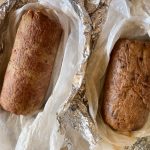 Polpettone di ceci al forno croccante 1 primo piano su un tavolo avvolto nella carta argentata un polpettone di ceci al forno, accanto u altro appena uscito dal forno