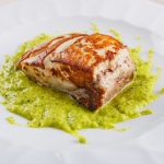 Ricciola al forno: un secondo piatto di pesce sano e gustoso 1 primo piano di un piatto con la ricciola al forno su un letto di crema di zucchine alla scapece servito in un ristorante elegante