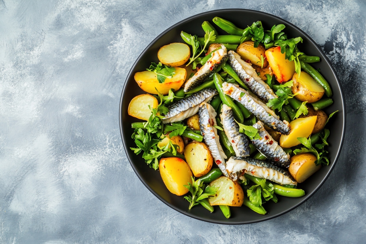 Sardine al forno: una ricetta light e saporita 2 su sfondo una teglia con sardine al forno pronto ad essere cotto con patate, fagiolini e prezzemolo