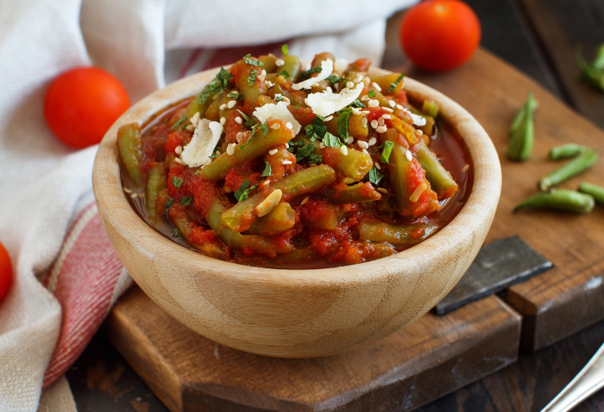 Ricette con fagiolini: 11 idee facili, gustose e nutrienti 2 su tavolo, tagliere con ciotola in marmo con fagiolini all'uccelletto con alcuni fagiolini lavati e tagliati e dietro pomodorini