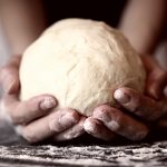 Pasta matta: la ricetta base per deliziose torte salate leggere 1 primo piano di mani di una donna che tiene in mano una palla di pasta matta dopo averla lavorata