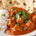 Pollo tikka masala: un secondo piatto indiano speziato 1 primo piano di un piatto bianco con riso basmati, pollo tikka masala e pane naan