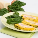 Rotolo di frittata al forno: una ricetta veloce e light 1 in primo piano un piatto verde chiaro con rotolo di frittata decorato con una foglia di spinacino