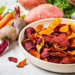 Chips di carote croccanti: la ricetta al forno e varianti 1 su tavolo piatto con chips di carote e barbabietole con attorno carote e barbabietole