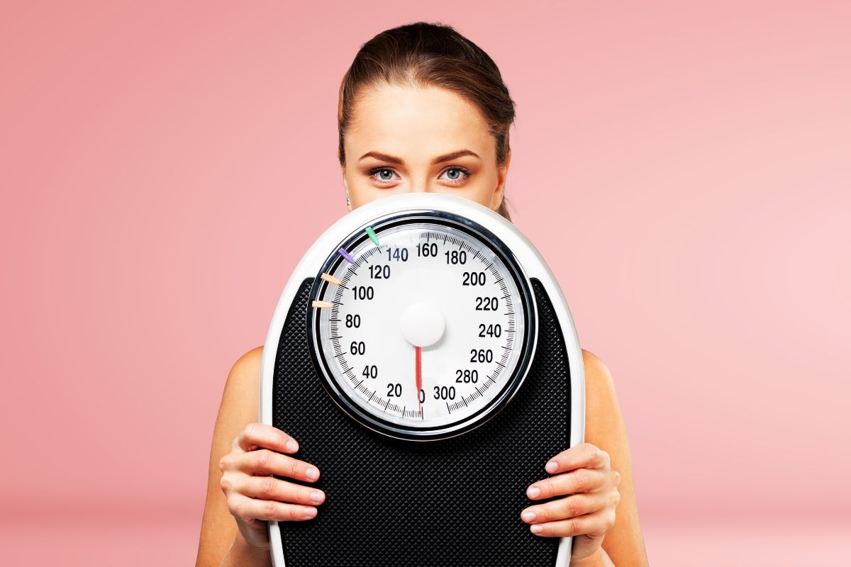dieta 1500 calorie: una donna che tiene una bilancia in mano