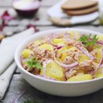 Insalata di patate e tonno: una ricetta semplice da preparare 1 in primo piano, in un piatto fondo bianco un'insalata patate e tonno con cipolla rossa