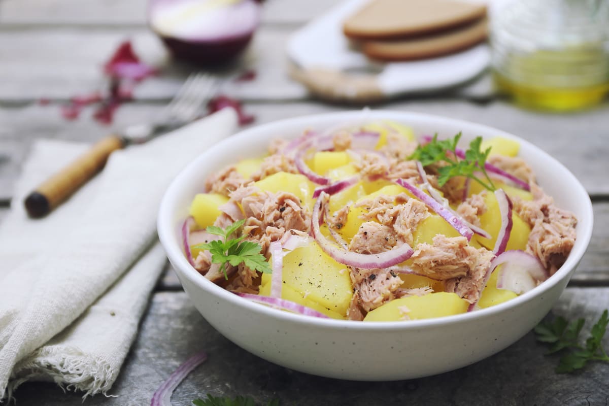 Ricette con le patate: le migliori da provare facilmente a casa 38 in primo piano, in un piatto fondo bianco un'insalata patate e tonno con cipolla rossa