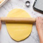 Pasta frolla senza burro: l'impasto leggero e goloso per crostate e biscotti 1 in primo piano la pasta frolla senza burro mentre viene stesa con un mattarello.