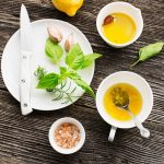 Citronette: la ricetta del dressing fresco e agrumato 1 su tavolo di legno ingredienti per preparare la citronette: sale, limone, olio erbe aromatiche, sale e la ciotola piena di emulsione