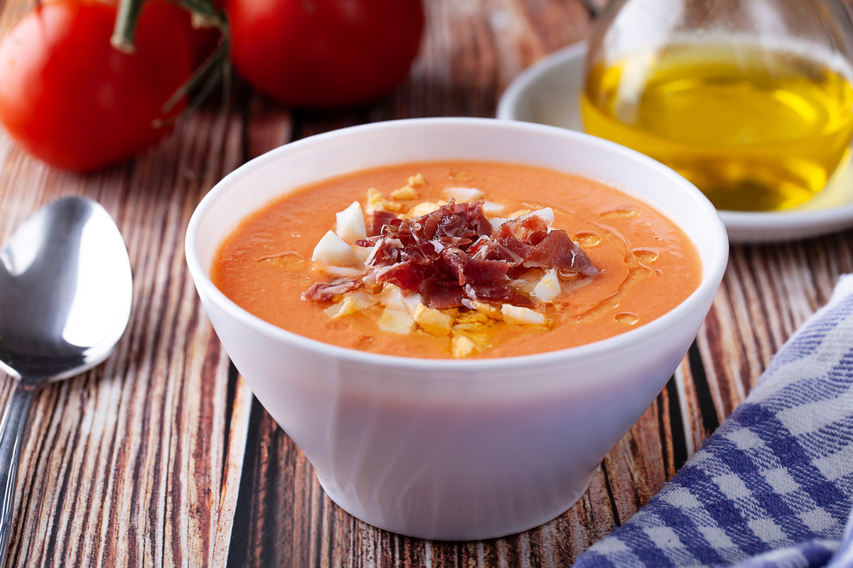 in primo piano dentro una ciotola bianca la zuppa fredda di salmorejo con uova sode e jamon serrano