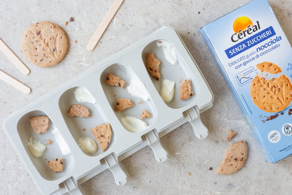 Gelato senza zuccheri aggiunti: ricetta fatta in casa 2 Una forma per 4 gelati a stecco, con dentro alcuni biscotti sbriciolati. Accanto una confezione di biscotti senza zuccheri Céréal