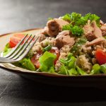 Cous cous estivo con tonno: una ricetta deliziosa 1 primo piano di un piatto sul tavolo con cous cous estivo con tonno, rucola, pomodorini e erbe aromatiche