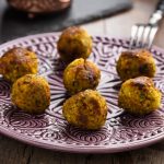 Polpette di cous cous con verdure al forno 1 su tavolo di legno piatto viola e bianco con 7 polpette di cous cous