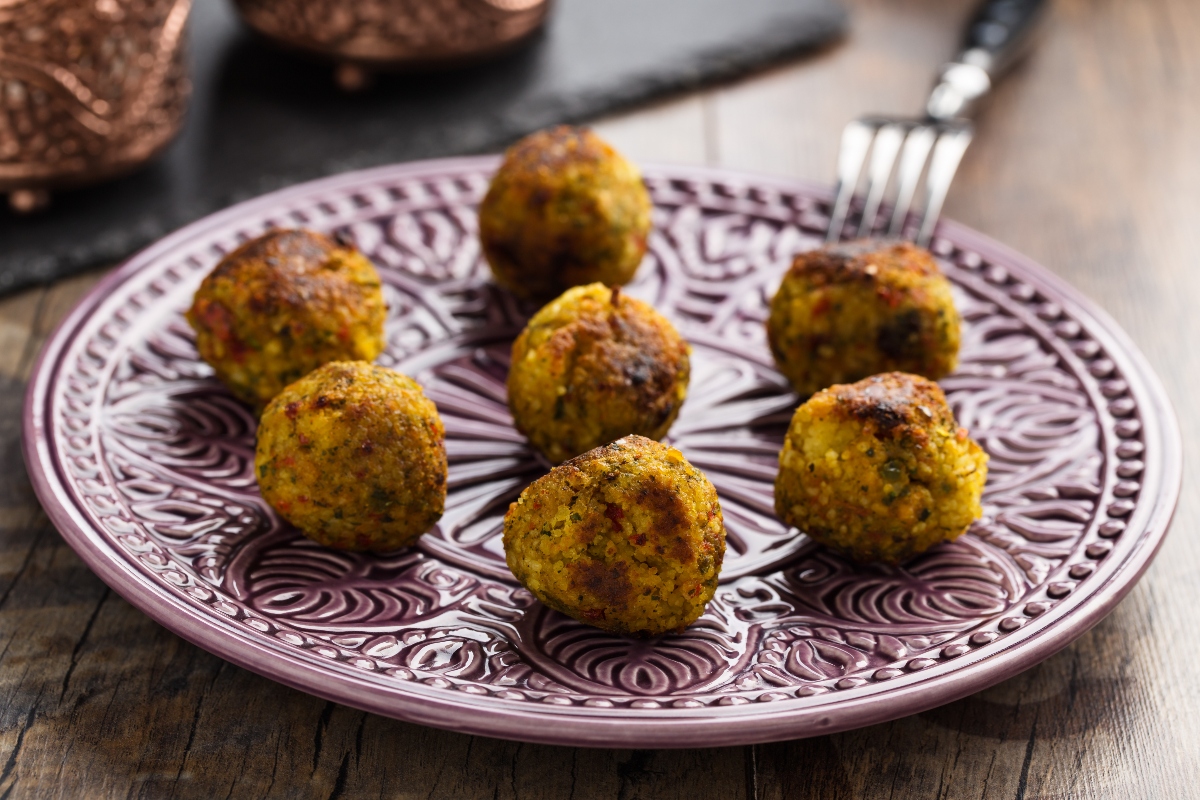 su tavolo di legno piatto viola e bianco con 7 polpette di cous cous