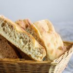 Focaccia genovese: ricetta tradizionale ligure soffice e fragrante 2 in primo piano delle fette di focaccia genovese appena sfornata, con impasto morbido e alveolato e una crosta dorata e fragrante, disposte in un cestino di vimini.
