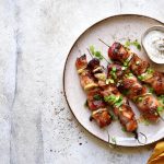 Souvlaki: la ricetta del delizioso spiedino greco 1 su tavolo di marmo, piatto con souvlaki di maiale, i famosi spiedini greci e salsa di yogurt