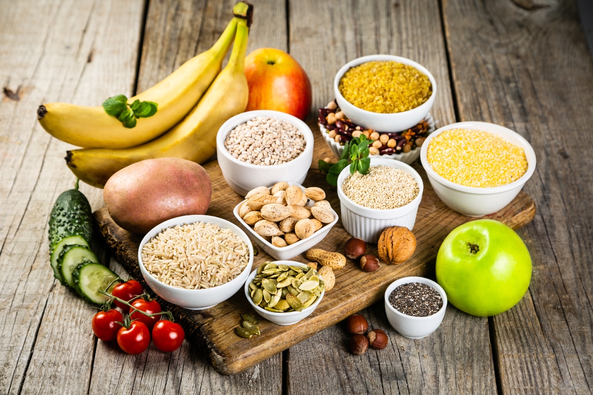 su tavolo di legno tagliere di legno con alimenti ricchi di zuccheri semplici: frutta come banane e mela, cereali, semi e frutta secca