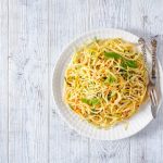 Pasta alla carrettiera: ricetta siciliana con variante al pomodoro pronta in 10 minuti 1 In primo piano un piatto di pasta alla carrettiera servito in un piatto bianco con erbe fresche e peperoncino su sfondo in legno chiaro.