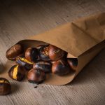 Castagne in friggitrice ad aria: una ricetta facile e veloce 1 su tavolo di legno, un sacchetto di carta con castagne in friggitrice d'aria pronte ad essere mangiate