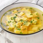 Zuppa imperiale: ricetta originale passo passo 1 Su tavolo di legno bianco ciotola con la zuppa imperiale con semolino, brodo di carne e uova