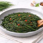 Agretti in padella: ricetta veloce con poche calorie 1 In primo piano su uno sfondo chiaro, ci sono degli agretti in padella conditi con del peperoncino.