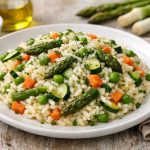 Risotto primavera perfetto: la ricetta perfetta, fresca e cremosa 1 piatto piano bianco pieno di risotto primavera con verdure miste